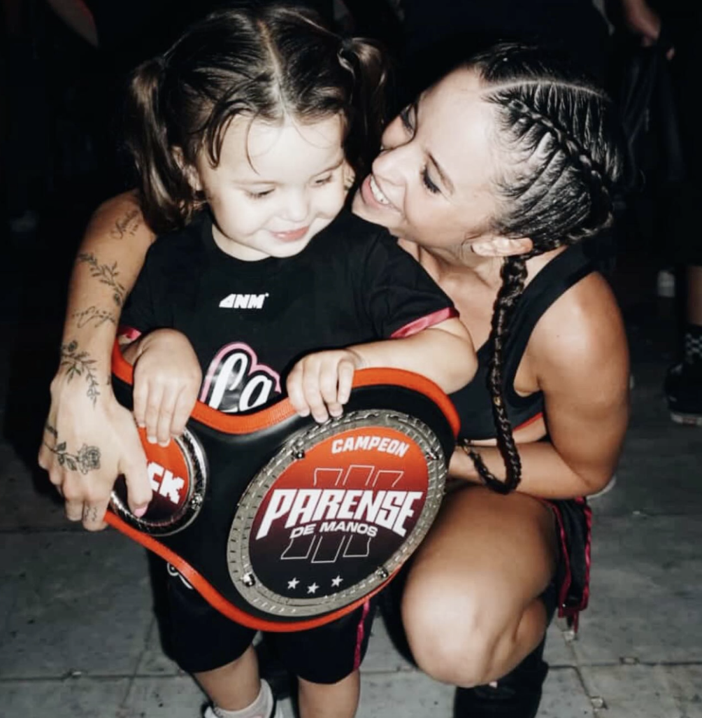 Caro con su hija Mía y el cinturón de campeona